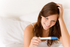 woman-looking-at-ovulation-test-results-smiling | American Pregnancy Association