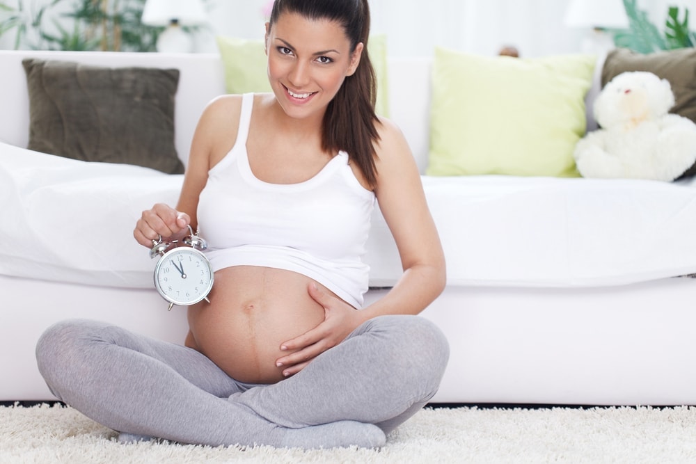 signs-of-labor-pregnant-woman-timer-sitting-smiling | American Pregnancy Association